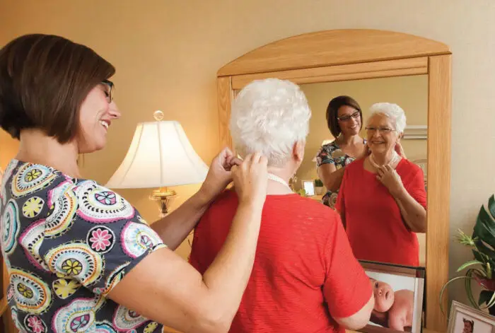 Lady putting a necklace on a senior citizen